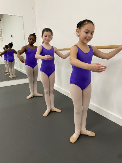 Group of 3 students in the 8 to 11 years class, practicing at the barre.
