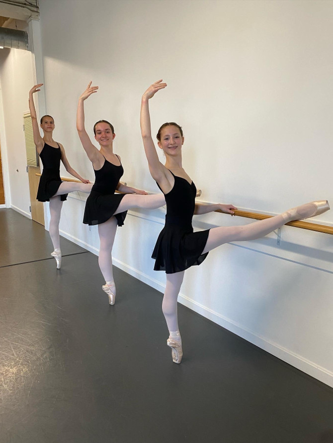 Three students practicing at the barre.