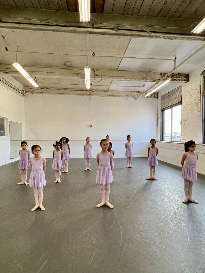 Group of Primary dancers standing in first position in studio 3.