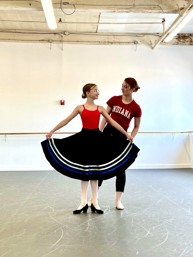 Dancer in character skirt and shoes interacting with instructor.
