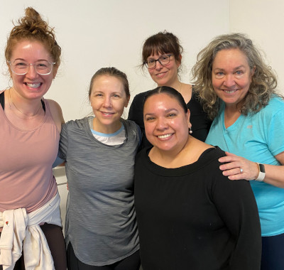 Happy, smiling participants in adult dance classes, posing for camera, arms interlinked.